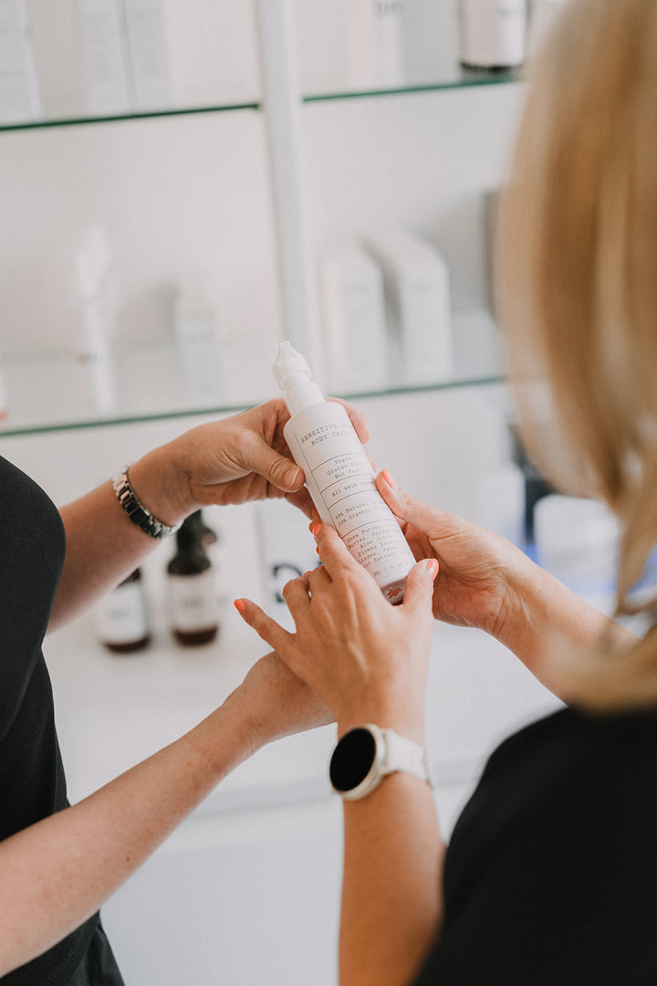 A practitioner showing a patient a skincare product in the clinic