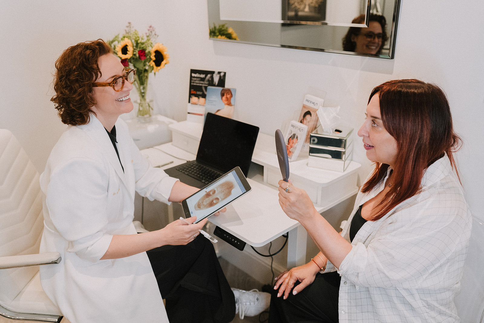 A Cosmetica doctor showing a patient her skin analysis on a tablet during a consultation